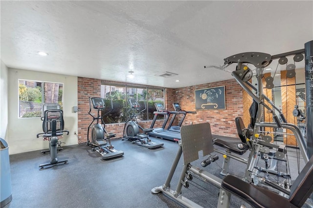 workout area featuring a textured ceiling and brick wall