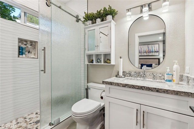 bathroom featuring vanity, toilet, and a shower with door