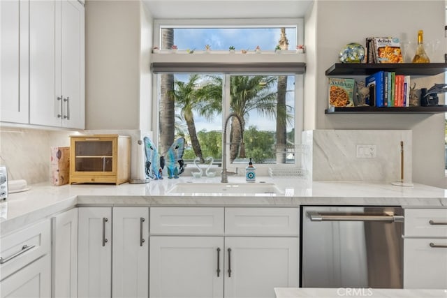 kitchen featuring light stone counters, sink, stainless steel dishwasher, and white cabinets