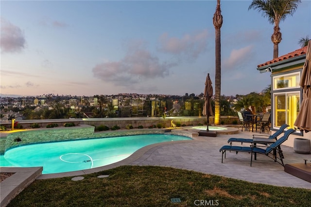 pool at dusk with a patio area