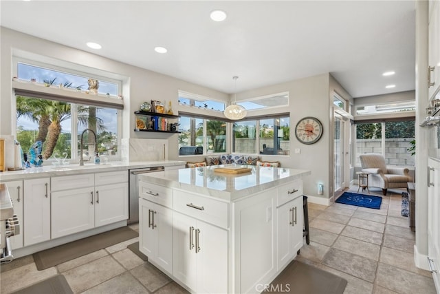 kitchen with sink, white cabinetry, a center island, hanging light fixtures, and stainless steel dishwasher