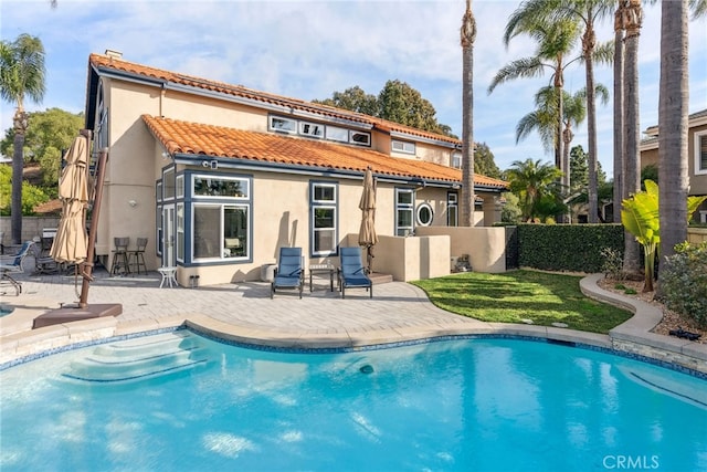 rear view of property with a fenced in pool and a patio area