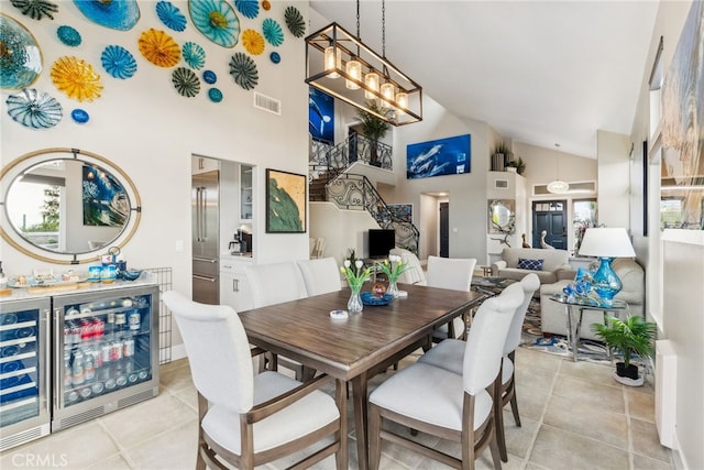 tiled dining space with an inviting chandelier, bar, beverage cooler, and high vaulted ceiling