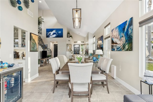 tiled dining area featuring plenty of natural light, high vaulted ceiling, and beverage cooler