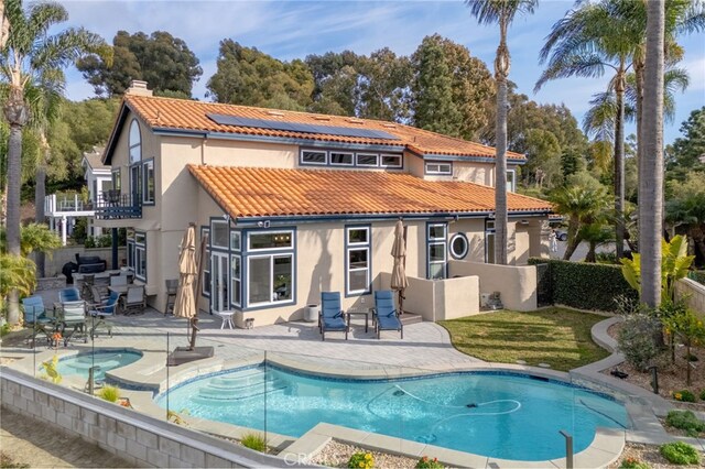 back of property featuring a balcony, a patio area, and solar panels