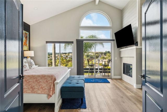 bedroom featuring high vaulted ceiling, access to outside, a fireplace, and light hardwood / wood-style floors