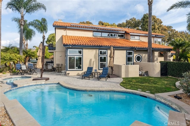 rear view of house featuring a swimming pool with hot tub and a patio