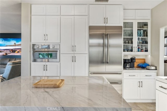 kitchen with light stone counters, appliances with stainless steel finishes, and white cabinets