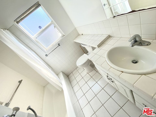 bathroom with tile patterned flooring, vanity, toilet, and tile walls