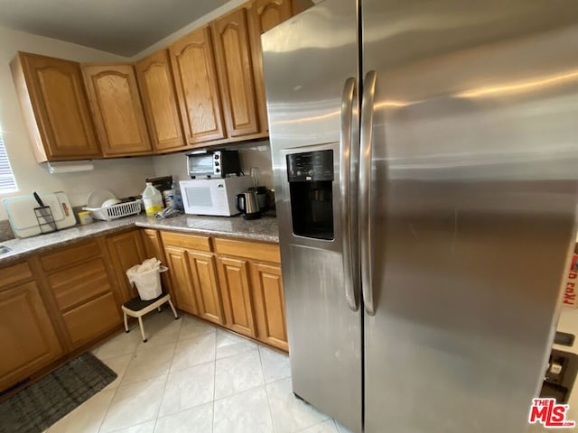 kitchen with light tile patterned floors and stainless steel refrigerator with ice dispenser