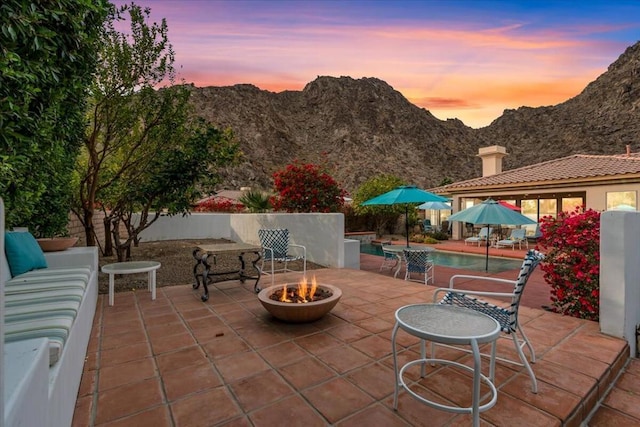 patio terrace at dusk with an outdoor fire pit and a mountain view