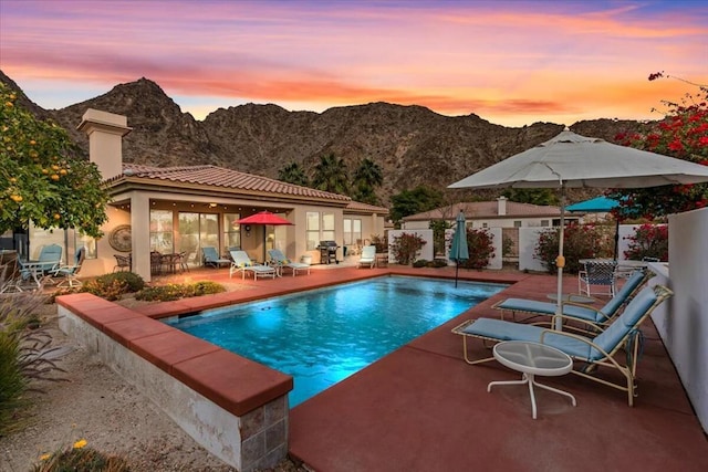 pool at dusk featuring a mountain view and a patio