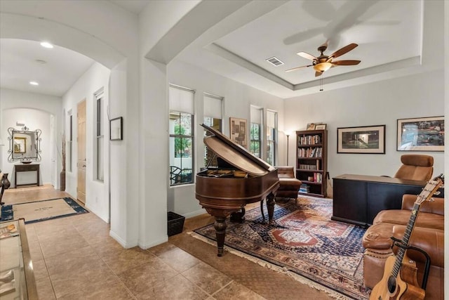 interior space featuring a raised ceiling, tile patterned floors, and ceiling fan