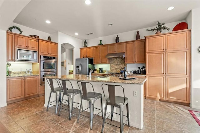 kitchen featuring stainless steel appliances, sink, a breakfast bar area, and a center island with sink