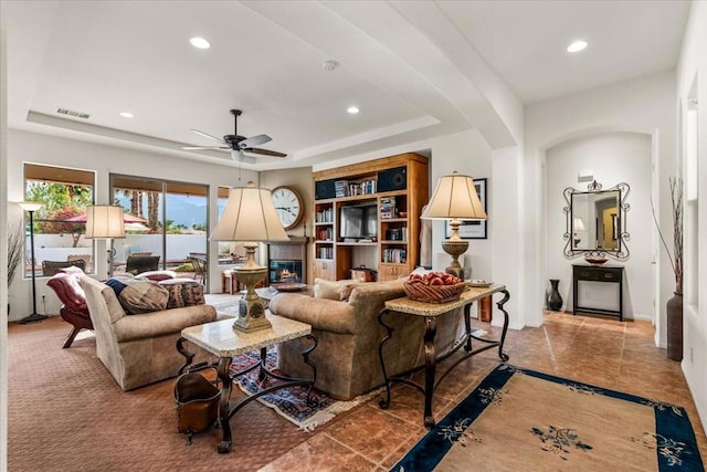 living room featuring a tray ceiling and ceiling fan