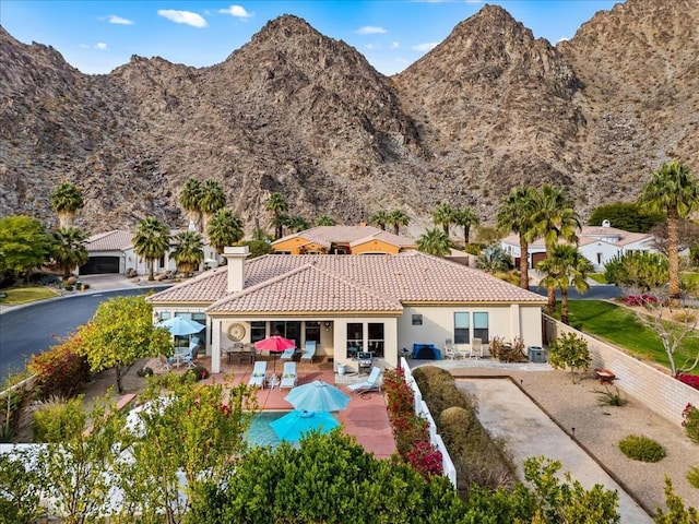 back of property with a mountain view and a patio area