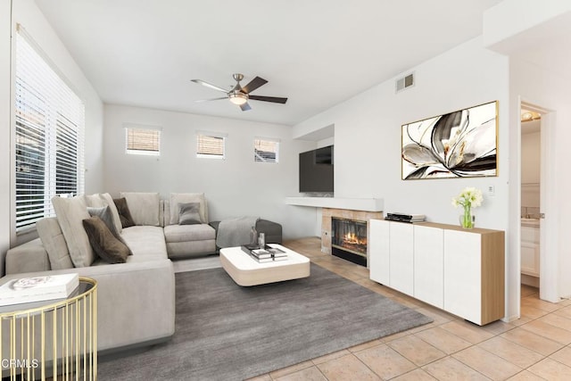 tiled living room featuring a tile fireplace and ceiling fan