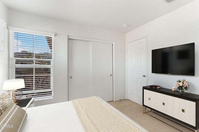 bedroom featuring light carpet and a closet