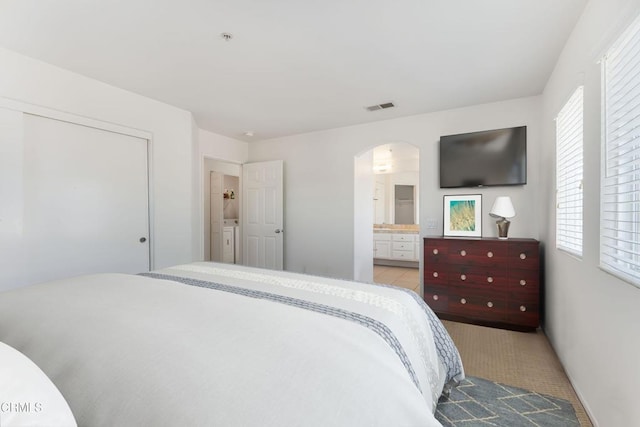 bedroom with multiple windows, connected bathroom, and separate washer and dryer