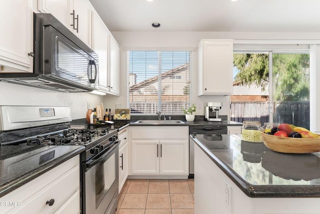 kitchen featuring white cabinetry, appliances with stainless steel finishes, sink, and dark stone countertops