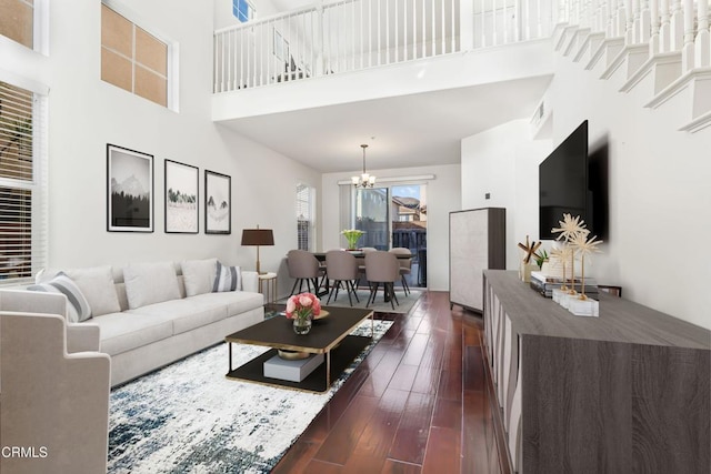 living room with dark hardwood / wood-style floors, a chandelier, and a high ceiling