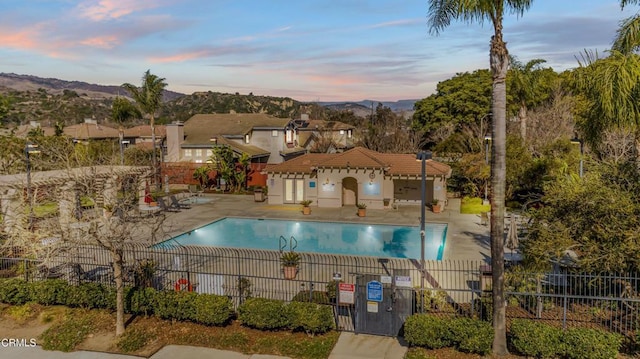 pool at dusk featuring a patio and a mountain view