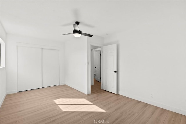 unfurnished bedroom featuring ceiling fan, light hardwood / wood-style floors, and a closet