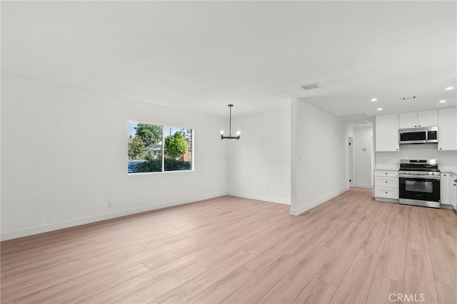 unfurnished living room with an inviting chandelier and light wood-type flooring