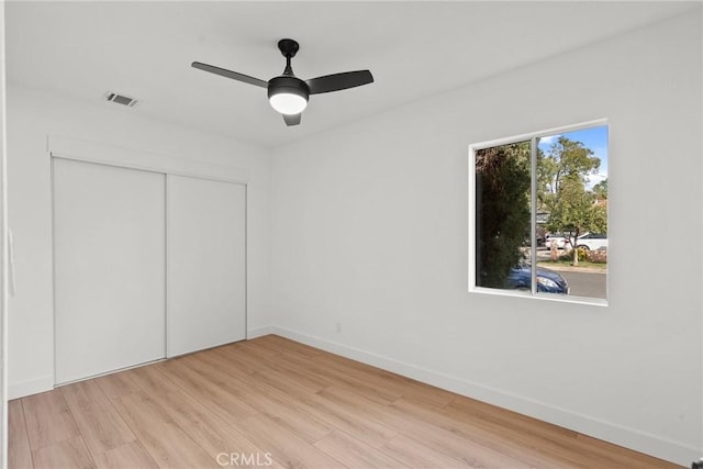 unfurnished bedroom featuring ceiling fan, light hardwood / wood-style floors, and a closet