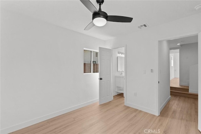 unfurnished bedroom featuring ceiling fan, ensuite bathroom, and light wood-type flooring