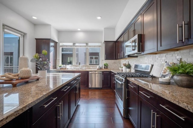 kitchen featuring light stone counters, dark brown cabinetry, and stainless steel appliances