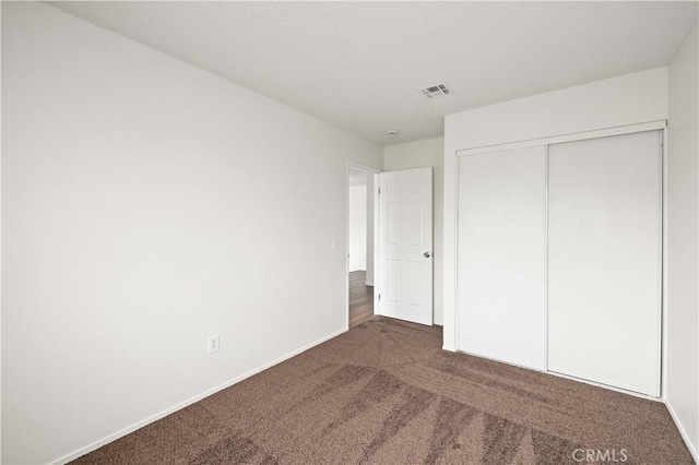 unfurnished bedroom featuring dark carpet and a closet