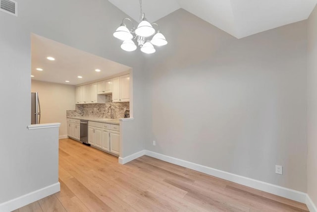 kitchen with appliances with stainless steel finishes, hanging light fixtures, light hardwood / wood-style floors, white cabinets, and decorative backsplash