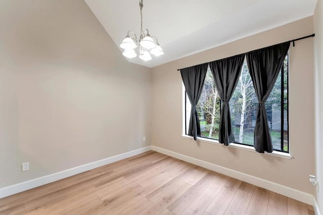 spare room with an inviting chandelier, light hardwood / wood-style flooring, and vaulted ceiling