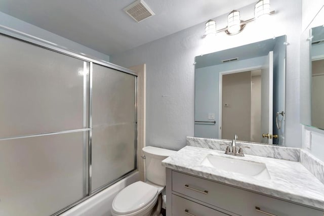 full bathroom featuring vanity, bath / shower combo with glass door, and toilet