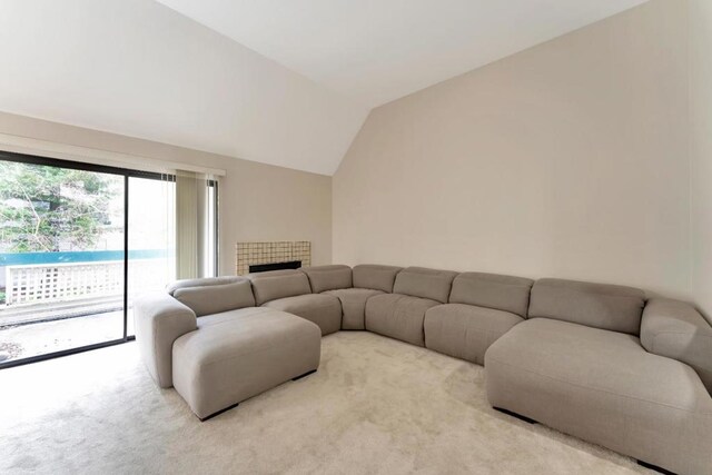 carpeted living room with vaulted ceiling and a fireplace