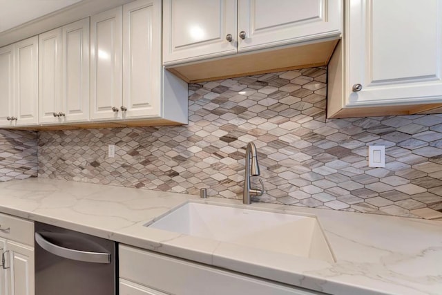 kitchen with white cabinetry, sink, and light stone counters