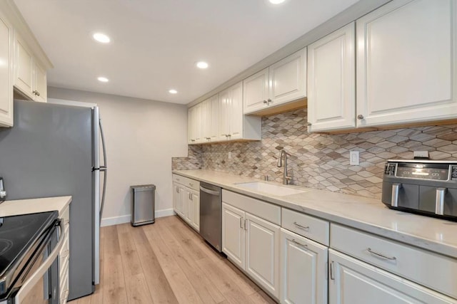 kitchen featuring white cabinetry, sink, light hardwood / wood-style flooring, and appliances with stainless steel finishes