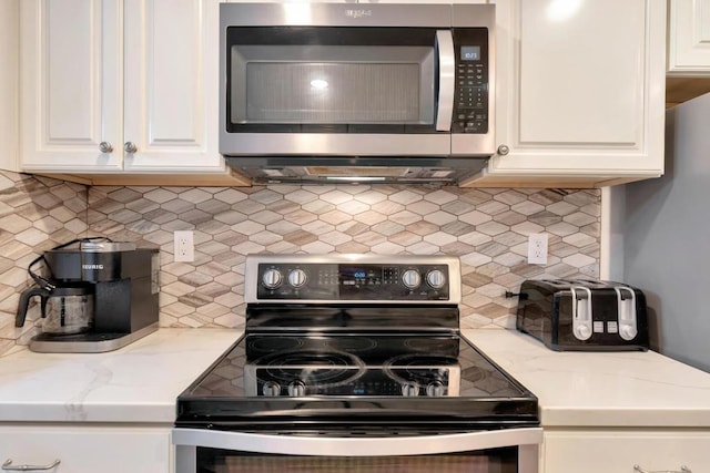 kitchen featuring light stone counters, decorative backsplash, stainless steel appliances, and white cabinets