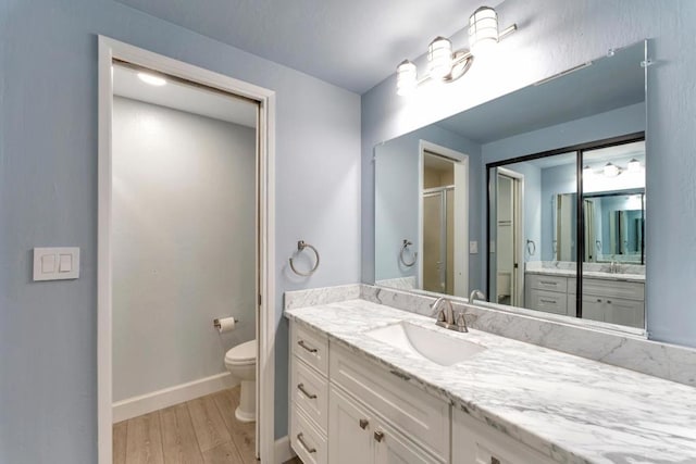 bathroom with vanity, hardwood / wood-style floors, toilet, and an enclosed shower