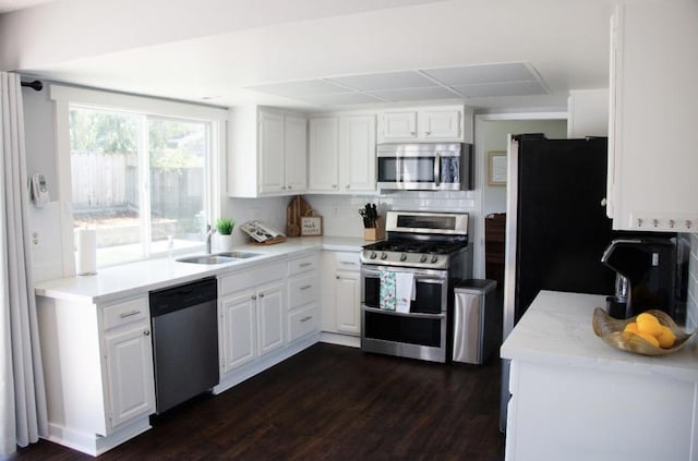 kitchen with dark wood-type flooring, sink, white cabinetry, appliances with stainless steel finishes, and backsplash