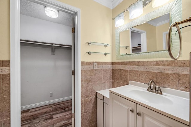 bathroom featuring ornamental molding, vanity, a textured ceiling, and tile walls