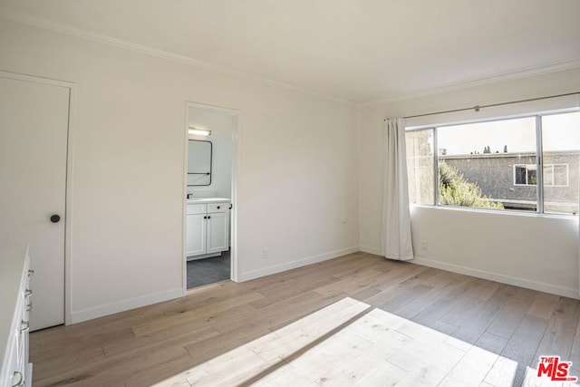 unfurnished bedroom featuring crown molding, light hardwood / wood-style flooring, and ensuite bath