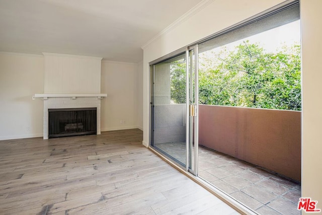 unfurnished living room with ornamental molding, a brick fireplace, and light hardwood / wood-style floors