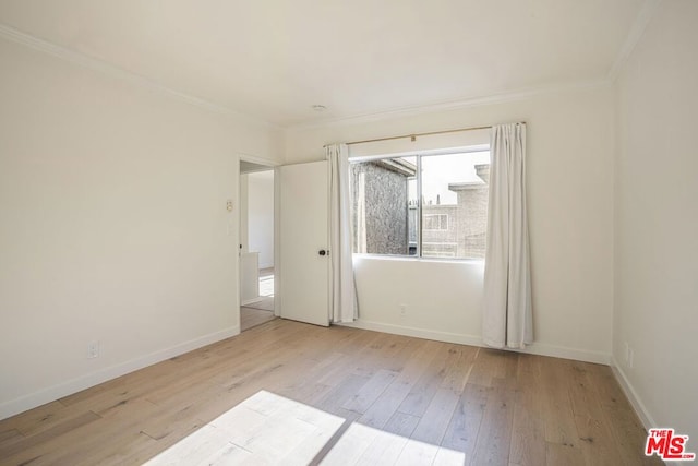 empty room with crown molding and light wood-type flooring