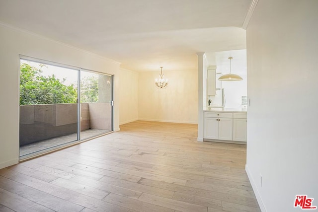 unfurnished room featuring crown molding, light hardwood / wood-style floors, and a notable chandelier