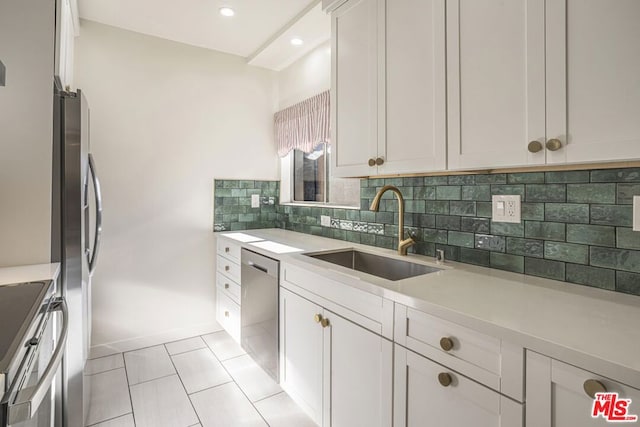 kitchen with sink, white cabinetry, light tile patterned floors, appliances with stainless steel finishes, and decorative backsplash