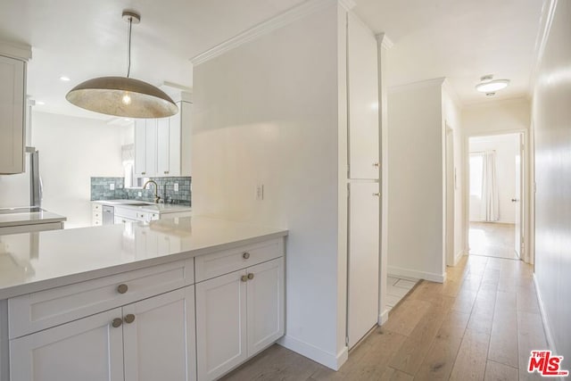 kitchen with stainless steel fridge, white cabinetry, backsplash, ornamental molding, and light wood-type flooring