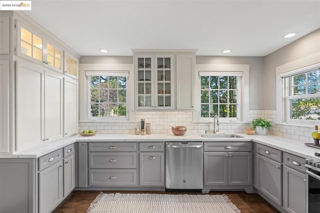 kitchen with dark wood-type flooring, sink, gray cabinetry, tasteful backsplash, and appliances with stainless steel finishes