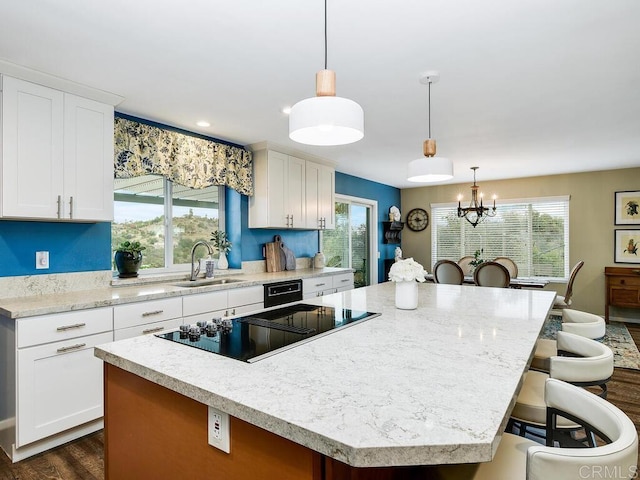 kitchen with sink, hanging light fixtures, white cabinets, and a center island